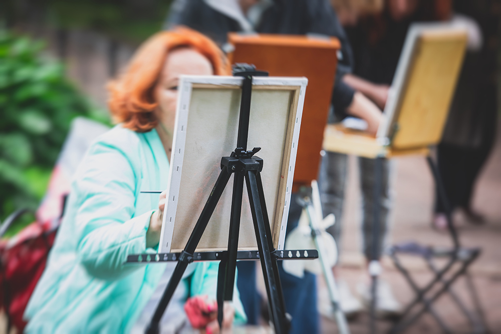 Artist painting en plein air with a lightweight metal easel