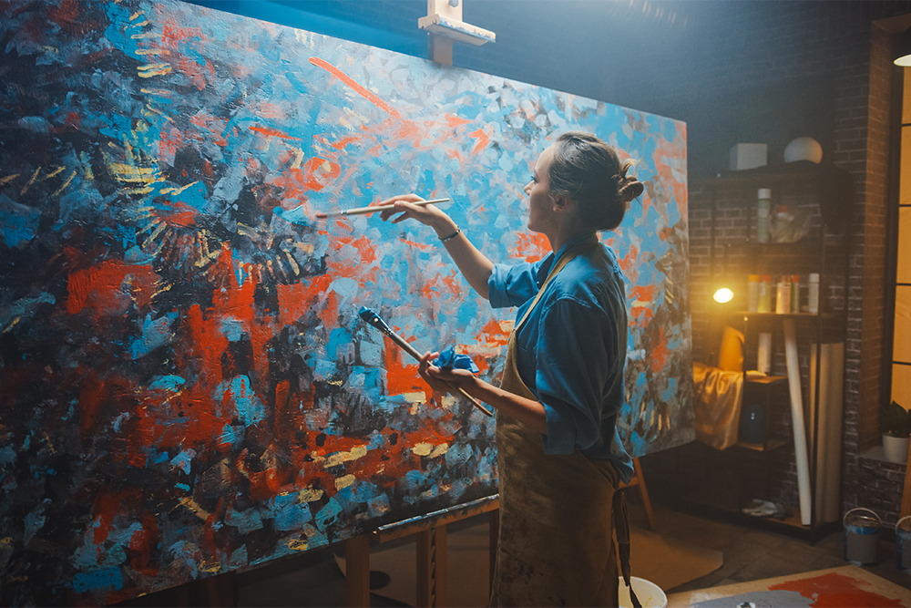 Female artists working on a large scale painting on a sturdy studio easel