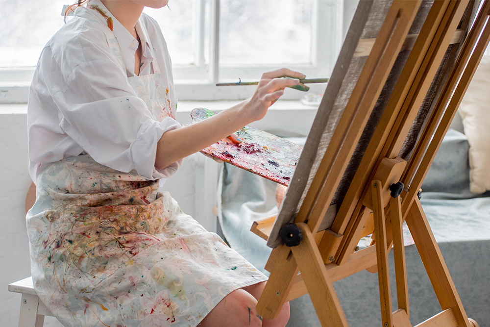 An artist working in acrylics sat at a studio easel
