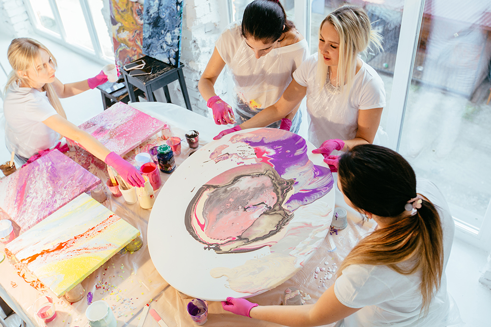 A group of artists creating fluid poured acrylic abstract contemporary paintings