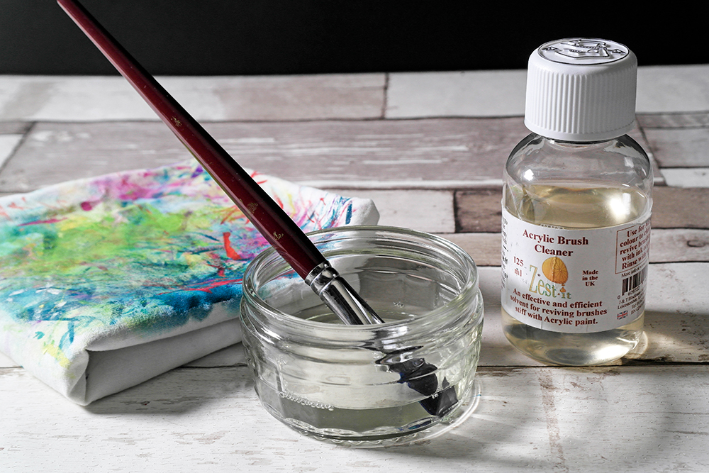 A dirty acrylic paint brush soaking in Zest It Acrylic Brush Cleaner