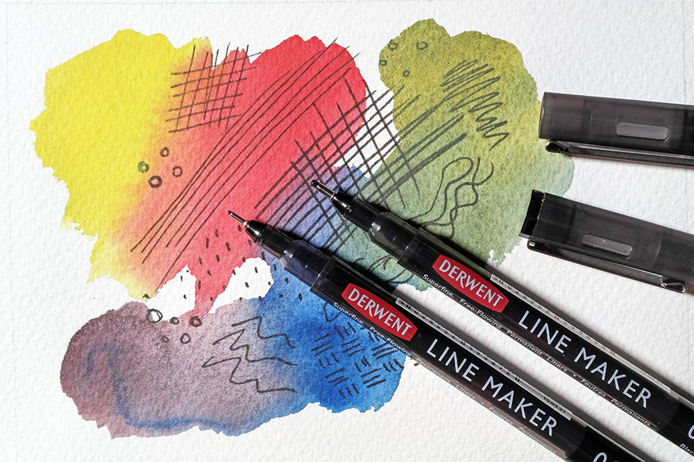 Two Derwent Line Maker fine liner pens in 0.3 and 0.8 are pictured. They rest on a sheet of paper painted with bold washes. Hatched pen marks are visible under the washes.