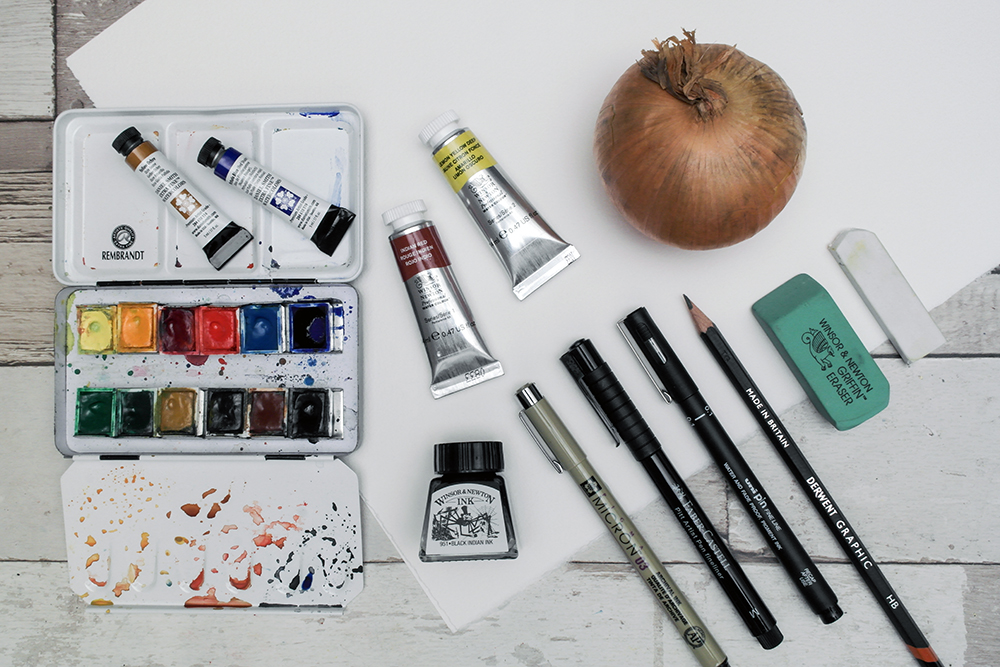 The materials needed for this Line and Wash tutorial by Liz Chaderton. Photograph shows watercolour paints, inks, fine liner pens, pencil and eraser.
