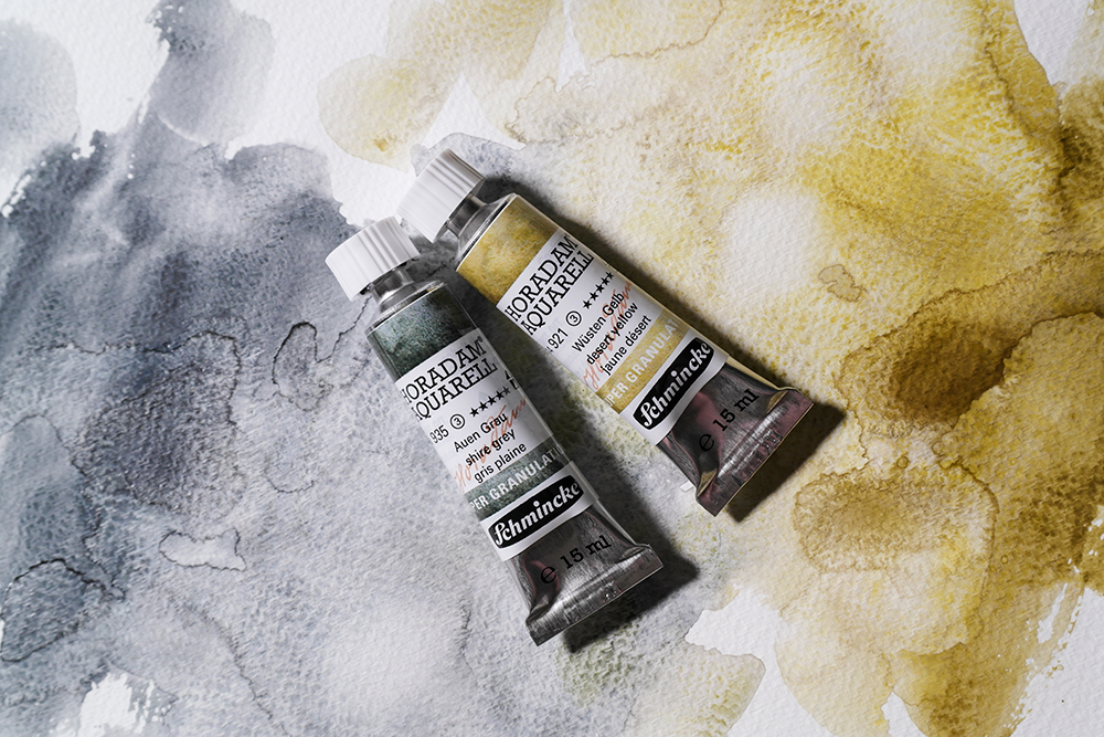 Schmincke Super Granulating Watercolour 15ml Tube Shire Grey and Desert Yellow photographed on a wash of both colours 14006935 14006921