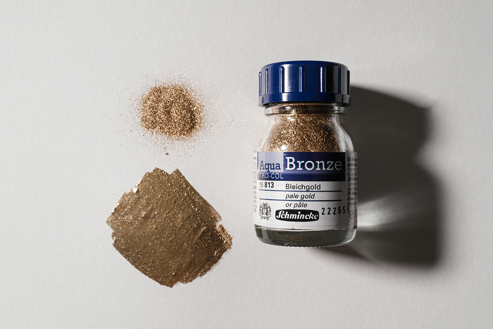 An image of the Aqua Bronze jar, alongside a pile of Aqua Bronze powder and a swatch of the powder mixed with water.