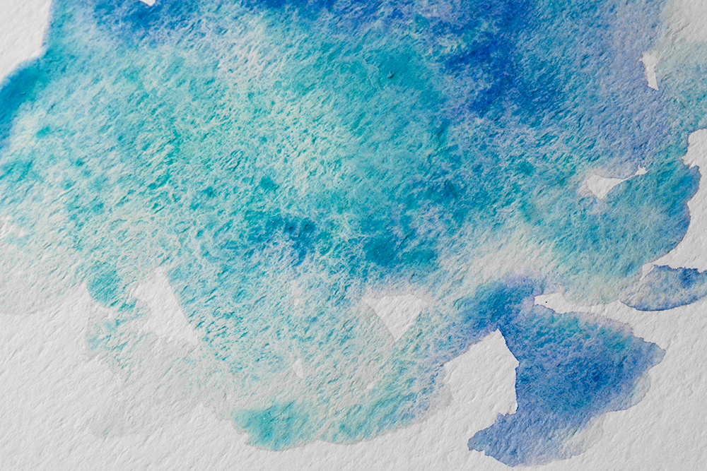 Granulating watercolour wash of blue and turquoise paint.