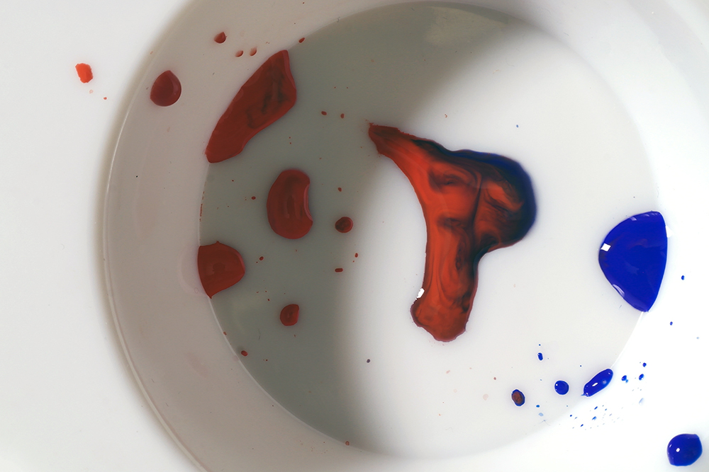 A plastic palette with a mixture of red and blue watercolour paint.