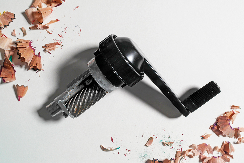 A helical blade and crank shaft from a manual crank sharpener on a white background.