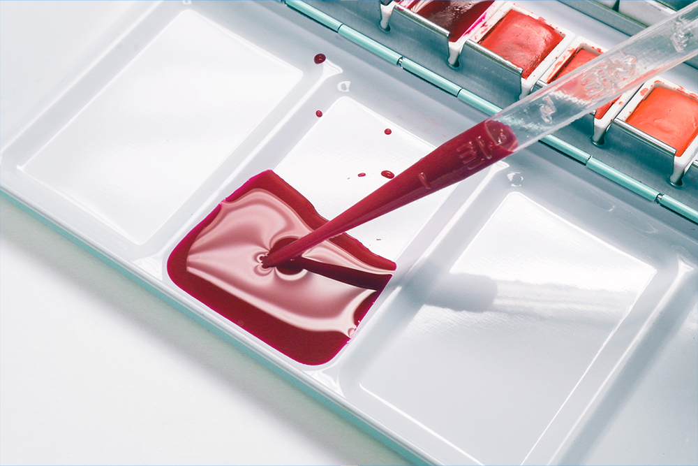 Filling a plastic pipette with dilute red watercolour paint