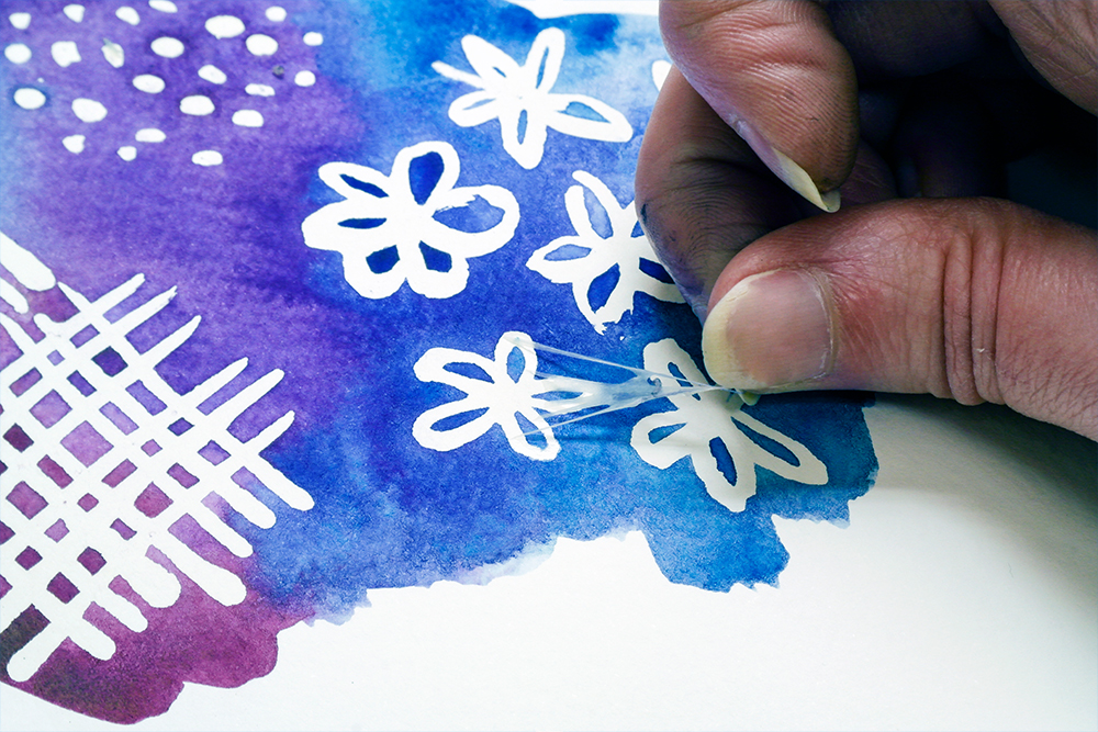 Artists' hand removing strings of masking fluid