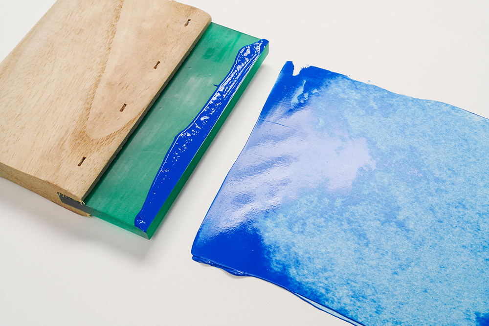 The Artful print making squeegee photographed with a stroke of blue acrylic ink
