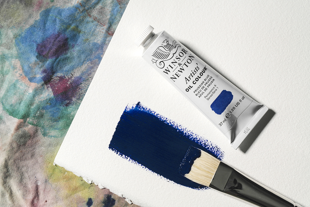 A tube of Winsor & Newton Artists Oil Colour next to a stroke of oil paint on oil painting paper