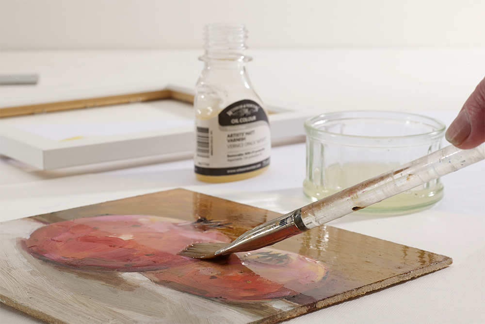 Artist painting a layer of gloss varnish onto an oil painting on panel