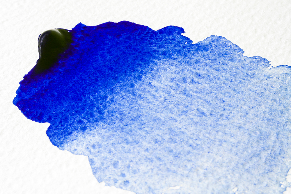 A detailed shot of a wash of French Ultramarine watercolour showing granulation