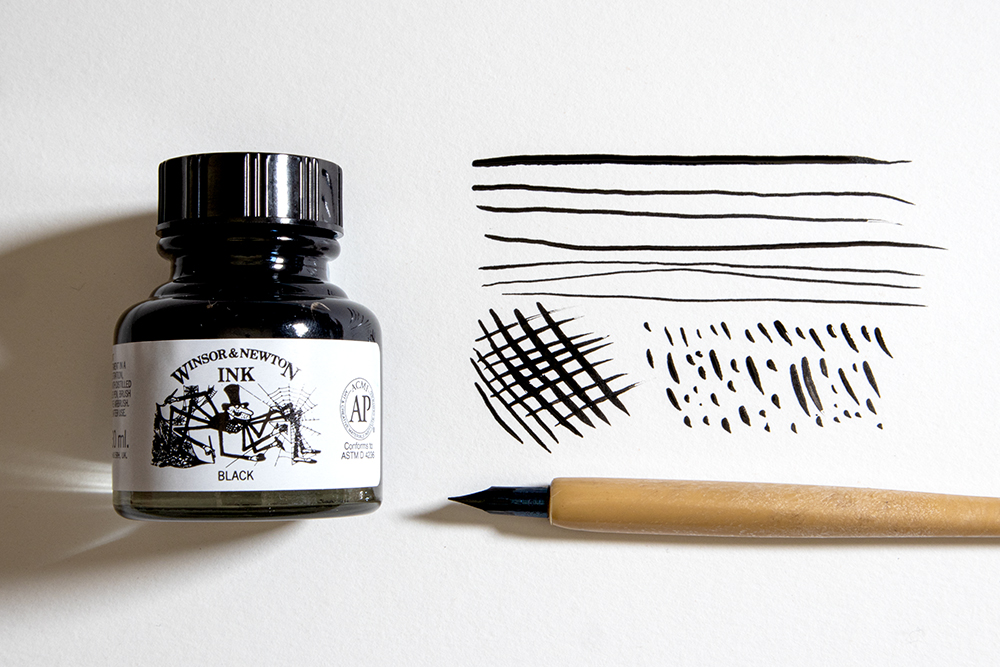 A bottle of Winsor & Newton Black Indian Drawing Ink and a dip pen alongside some hand drawn pen strokes.