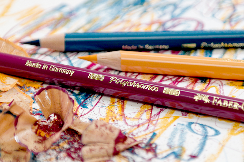 Three pencils from the Faber-Castell Polychromos coloured pencil range in turquoise, orange and purple.