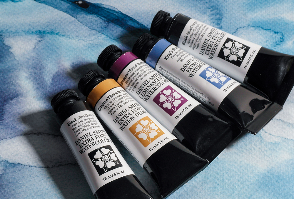 Five tubes of Daniel Smith Extra Fine Watercolour Paints on a painted background